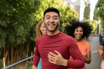 group of diverse male and female friends running around doing sports, focus on smiling asian man.