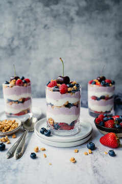 Close up of mixed berry yogurt parfaits on grey background.