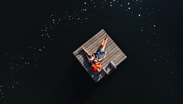 Couple laying together on swim platform on lake in summer.