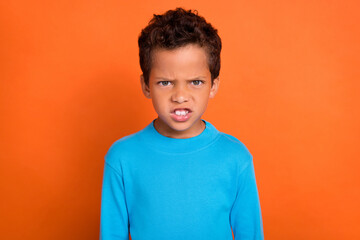Photo of disappointed dissatisfied boy worried bad situation dressed blue stylish jumper isolated on orange color background