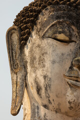 Close-up of the face of an ancient Buddha statue in a temple in Sukhothai Historical Park, Thailand