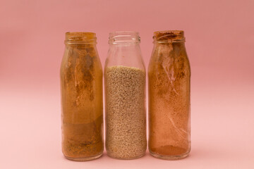 Spices in glass jars on a pink background