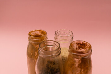 Spices in glass jars on a pink background