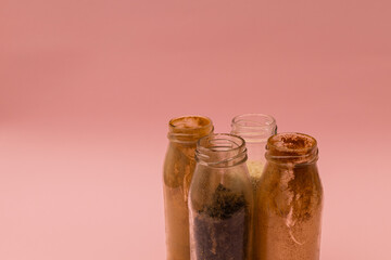 Spices in glass jars on a pink background