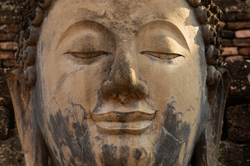 Fototapeta na wymiar Close-up of the eye and face of an ancient Buddha statue in a temple in Sukhothai Historical Park, Thailand