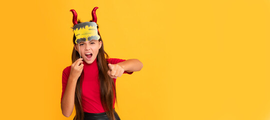 devil kid with pumpkin. trick or treat. teen girl point finger on yellow background. Halloween kid...