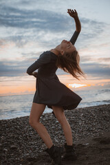 woman dances on the seashore at sunset. Psychology of soul and body dance grace