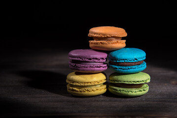 Macaroon cakes on wooden table and dark background