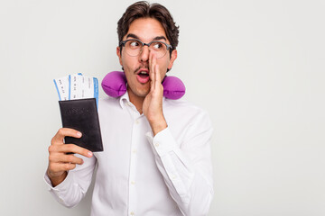 Young hispanic man with inflatable travel pillow holding passport isolated on white background is saying a secret hot braking news and looking aside