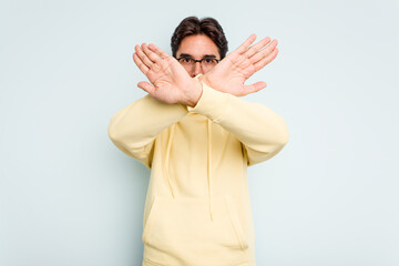 Young hispanic man isolated on blue background doing a denial gesture