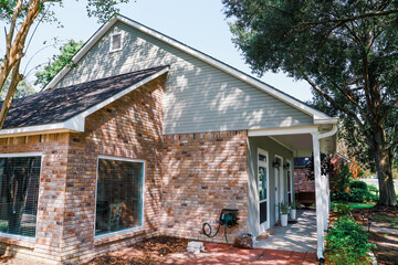 A side view of an Acadian renovated siding home a brick breakfast nook area