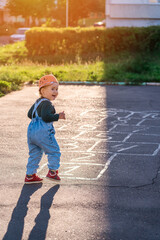 Fototapeta premium A kid plays hopscotch on the playground during sunset