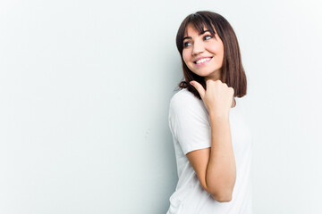 Young caucasian woman isolated on white background points with thumb finger away, laughing and carefree.