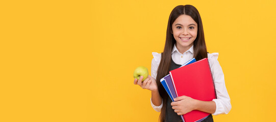 Happy kid back to school holding apple and books yellow background, education. Horizontal isolated poster of school girl student. Banner header portrait of schoolgirl copy space.