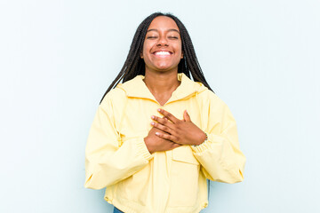 Young African American woman with braids hair isolated on blue background laughing keeping hands on heart, concept of happiness.