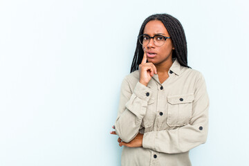 Young African American woman with braids hair isolated on blue background looking sideways with doubtful and skeptical expression.