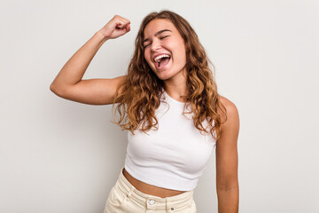 Young caucasian woman isolated on blue background celebrating a victory, passion and enthusiasm,...