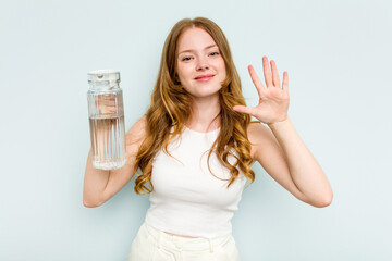 Young caucasian woman holding jar of water isolated on blue background smiling cheerful showing number five with fingers.