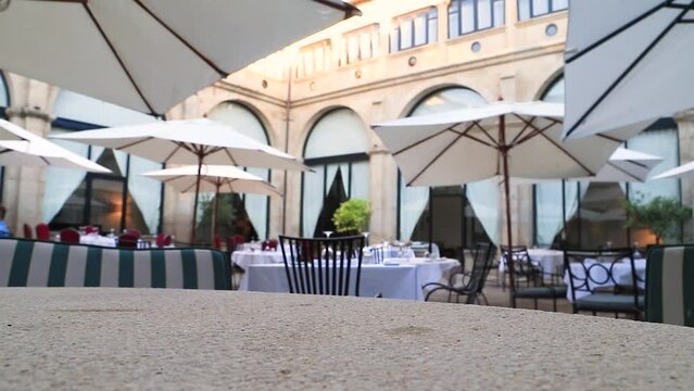 A hand holding a glass of cold cola. A glass of cola with ice, bubbles and a slice of lemon. On the terrace of a restaurant. Concept of good service and decoration.