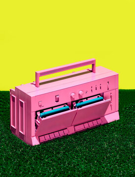 Pink retro tape recorder on grass in studio