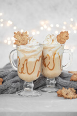 Pumpkin spice latte in a glass mug with caramel and cinnamon cookies with Autumn decoration