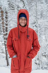 Portrait of teenage boy walking and having fun in winter snowing forest
