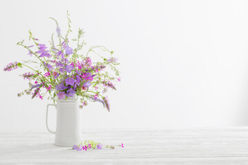 summer wild  flowers  in white jug on white background