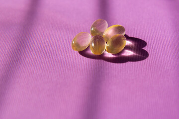 Omega 3 transparent capsules on a violet background. Dietary supplements and pills for dieting. Medical concept. Complementary and medical products