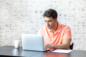 Young handsome man working on laptop at home. Distance work and online education concept	