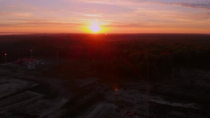 Fototapeta premium Bright sunset over the horizon in the tundra where oil and gas are extracted. A drone view of the sunrise in Siberia. Sunset over the extraction of fossil fuels in the global economy. Oil production.