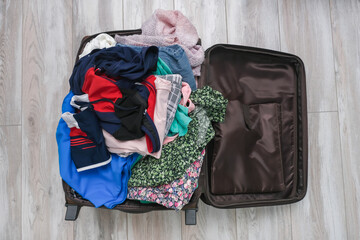 Open suitcase on the floor with a messy pile of clothes, getting away from home in a hurry