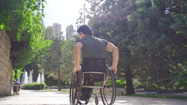 Disabled man in wheelchair moves on the road.
Young man in wheelchair outdoors.
