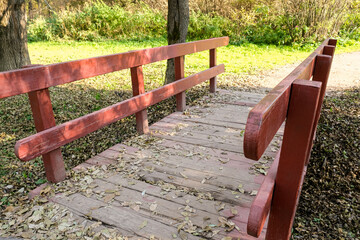 Small wooden brodge with red railings in a park in sunny day