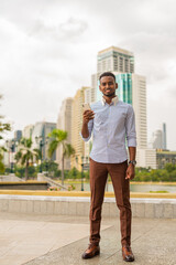 Handsome young black businessman at park using mobile phone