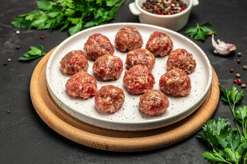 raw meatballs on wooden board, minced pork meat with spices on a dark background. banner, menu, recipe place for text, top view