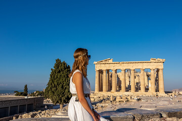 Rear view of tourist woman in white dress looking at Parthenon of Acropolis of Athens, Attica,...