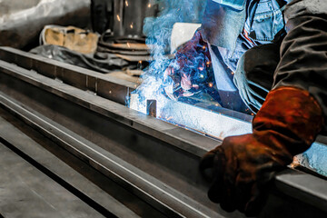 A metal welding worker is engaged in welding in a workshop.