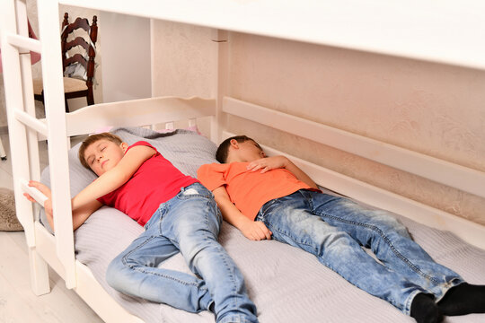 Two teenage brothers were playing and fell asleep dressed on the bed.