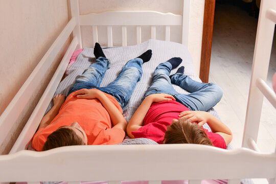 Two teenage brothers were playing and fell asleep dressed on the bed.