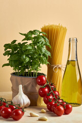 Food background, healthy mediterranean concept of
organic ingredients.
Still life with olive oil,tomato,garlic,basil leaves and raw pasta on beige background. Top wiev with copy space