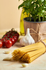 Food background, healthy mediterranean concept of
organic ingredients.
Still life with olive oil,tomato,garlic,basil leaves and raw pasta on beige background. Top wiev with copy space