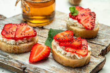 Crostini or toasts with strawberries and cream cheese ricotta. Delicious breakfast or snack, Clean eating, dieting, vegan food concept. top view