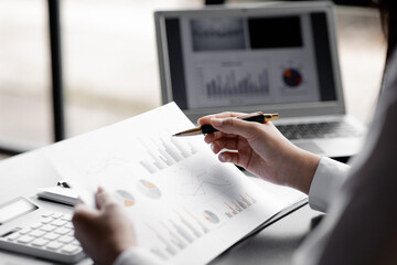 A close-up view of a businessman pointing at a bar chart on a company financial document prepared...