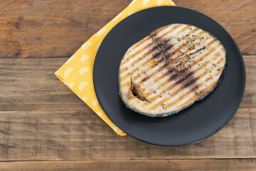 Grilled tuna slice on a wooden plate. Copy space. Top view. Thunnus.