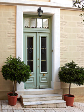 Cozy classic design house entrance, olive green door and potted plants. Athens old town center, Greece.