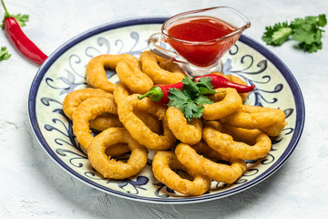 Rings of squid with lemon and sauce on a light background. Snack to beer. banner, menu, recipe place for text, top view