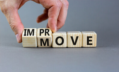 Move and improve symbol. Concept words Move and Improve on wooden cubes. Businessman hand. Beautiful grey table grey background. Business Move and Improve concept. Copy space.