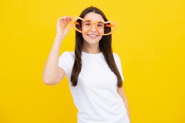 Girl with heart shaped glasses funny and smiling on yellow studio background.