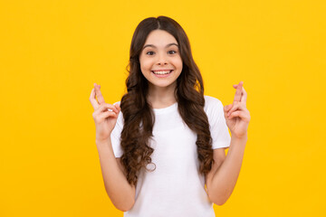 Teenager child holding fingers crossed for good luck. Portrait of cheerful girl prays and hopes...