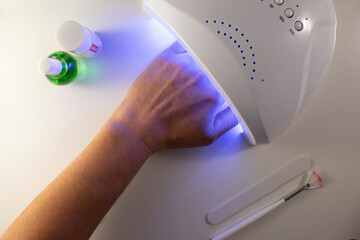 hand in lamp for drying gel polish manicure tools on a